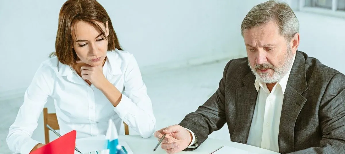 Business consultation meeting with a professional advisor discussing documents with a client at an office desk